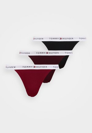 Drie paar Tommy Hilfiger slipjes in zwart, bordeauxrood en diep rood met een witte elastische tailleband waarop het merklogo staat afgebeeld.