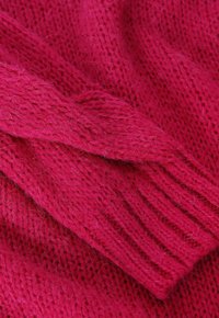 Tejido de punto fucsia con un patrón texturizado. Detalles de canalé visibles y fibras suaves y peludas en toda la superficie.