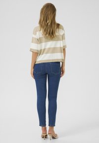 Beige och vit randig kortärmad topp tillsammans med tajta blå jeans, som visar en avslappnad design och len textur.