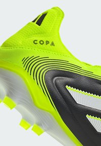 Geel en zwarte voetbalschoenen met een gestructureerde bovenkant, gebogen ontwerp en opvallende Copa-branding, voorzien van doorzichtige rubberen noppen voor grip.