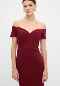 Burgundské šaty s odhalenými rameny, přiléhavého střihu, s výstřihem do V, krátkými rukávy a hladkým povrchem. Jednoduchý a elegantní design.