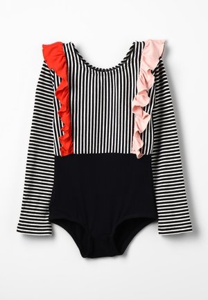 Traje de baño de manga larga con rayas en blanco y negro, acentos de volantes rojos y rosados en un hombro, y parte inferior negra sólida. Tejido suave.