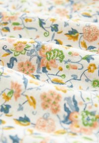 Katoenen stof met bloemenpatroon, gekenmerkt door kleine pastelgekleurde bloemen in roze, geel en blauw op een witte achtergrond met een zachte, gestructureerde weving.