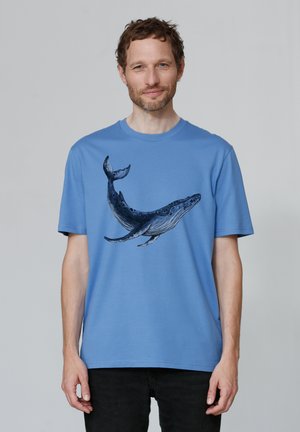 T-shirt en coton bleu avec un graphique de baleine imprimé sur le devant dans des tons sombres. Manches courtes et coupe décontractée.