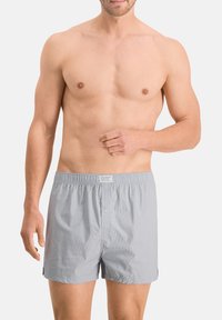 Grau karierten Boxershorts aus leichtem Stoff, mit elastischem Bund, Knopfverschluss und seitlichen Schlitzen für Komfort und Bewegungsfreiheit.