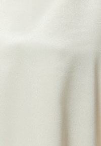 Tela de satén crema que presenta una textura suave y brillante con sutiles reflejos de luz, con un diseño minimalista sin patrones ni acentos.