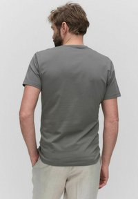 Grijze katoenen t-shirt, korte mouwen, ronde hals, fitted ontwerp, gladde textuur, achteraanzicht, gedragen met lichte broek.