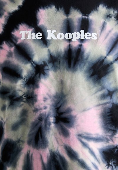 Tie-dye T-skjorte med virvlende mønstre i svart, grått og rosa, med "The Kooples" trykt i fet hvit tekst i midten.