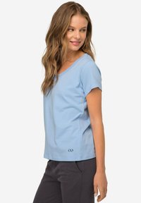 T-shirt di cotone blu chiaro con maniche corte e scollatura ampia, caratterizzato da un'accenno di logo sulla parte inferiore.