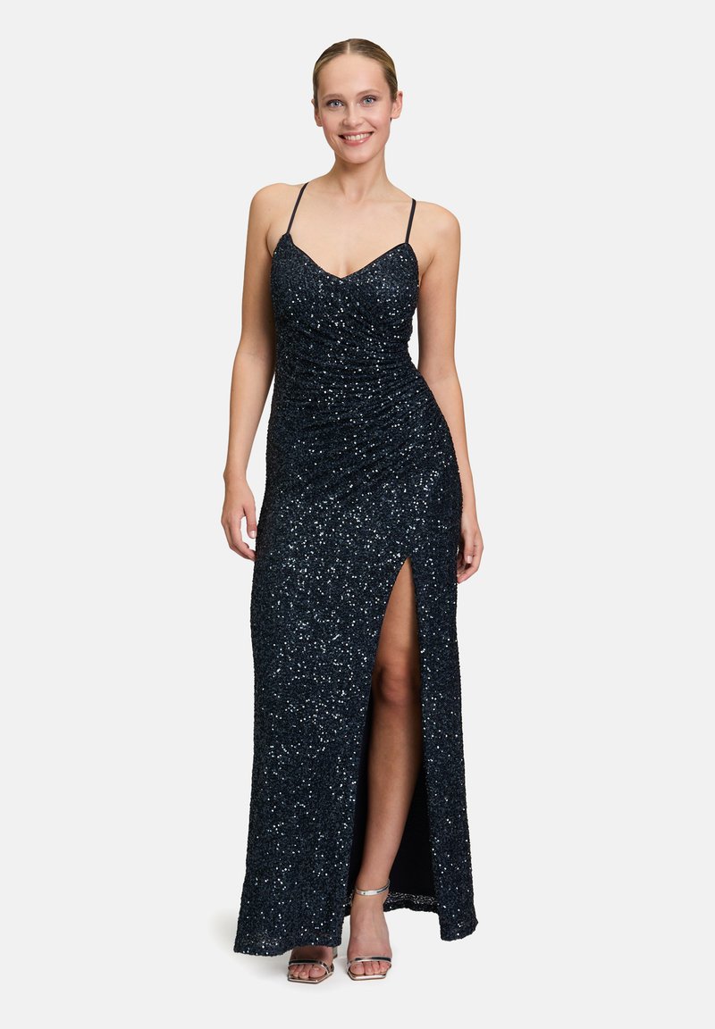 Langes, dunkelblaues Abendkleid mit Pailletten, schmalen Trägern, gerafftem Design und einem Seitenschlitz. Glatte Textur mit einer taillierten Silhouette. Silberne Akzente an den Schuhen.