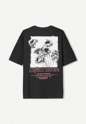 Black cotton t-shirt with short sleeves featuring a white floral print and "Safe Haven" in pink text at the back, rectangular graphic design.