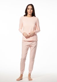 Lichtroze top met lange mouwen gecombineerd met een patroon van lichtroze en witte pyjamabroek. Zachte stof en aansluitende manchetten op de broek.