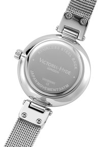 La tapa trasera de acero inoxidable del reloj presenta un acabado suave, el nombre de la marca grabado "Victoria Hyde" y una correa de malla con un cierre metálico.