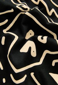 Tissu noir avec un motif abstrait de visage couleur crème, comprenant les yeux, le nez et la bouche formés par de simples lignes courbes.
