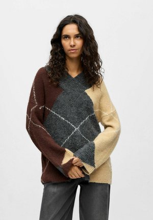 Pull-over oversized en V, avec un motif argyle, présentant des sections marron, gris et beige. Fabriqué en laine mélangée douce et texturée.