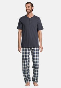 Maglietta henley a maniche corte blu navy con tre bottoni, abbinata a pantaloni del pigiama a quadri in blu, bianco e grigio. Realizzata in morbido cotone.