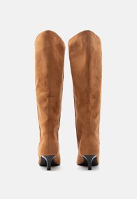 Καστόρινα καφέ μπότες πάνω από το γόνατο με λεπτό σχήμα και μαύρο στιλέτο τακούνι 3 ιντσών. Ομαλή υφή χωρίς ορατό εξάρτημα ή σχέδια.