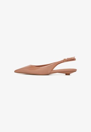Zapatos de tacón bajo tipo slingback en color nude, hechos de charol, con puntera afilada y correa ajustable con hebilla, que presenta un detalle con corte en el talón.