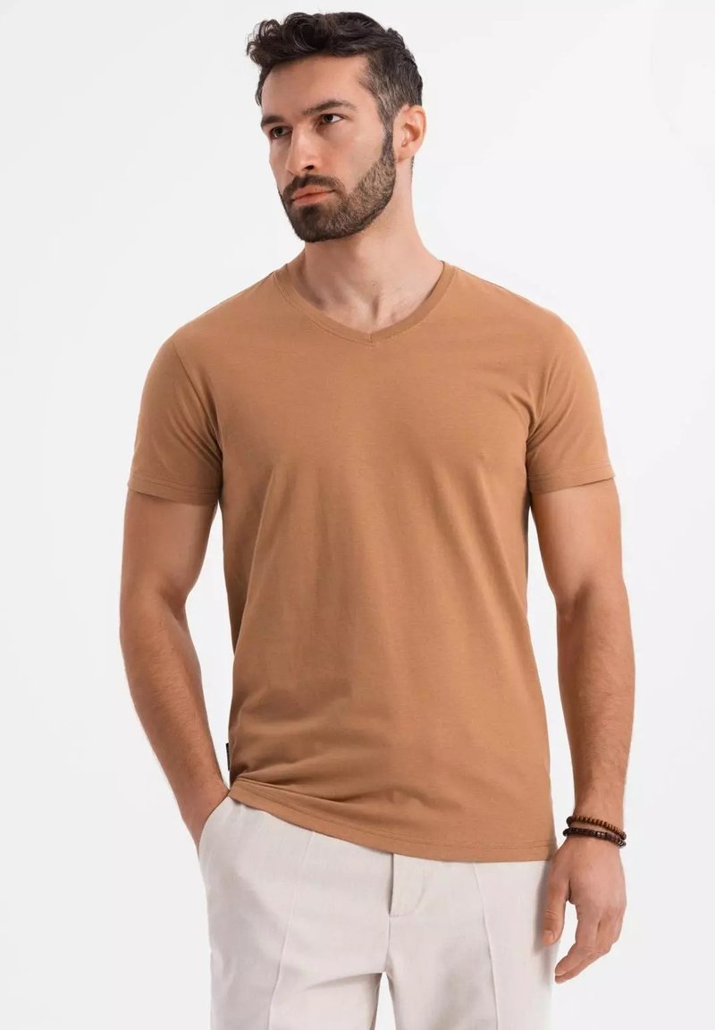 T-shirt a maniche corte, con scollo a V di colore marrone chiaro, realizzato in materiale morbido con una vestibilità slim. Presenta una texture liscia e un design minimal.
