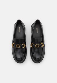 Mocassins en cuir noir avec un accent de chaîne dorée ornée d'un logo "G", bout rond et semelle intérieure rembourrée pour le confort.