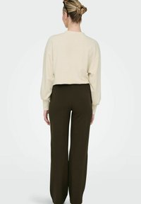 Ljust beige oversized sweatshirt i kombination med mörkbruna vida byxor. Mjuk vaddering och avslappnad passform; minimalistisk design utan dekorationer.