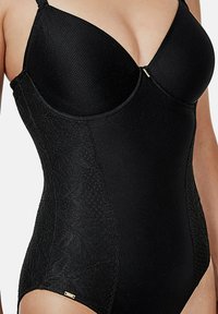 Zwarte bodysuit met gevormde cups, textuurstof en kantaccenten aan de zijkanten. Heeft verstelbare schouderbanden en een goudkleurig detail aan de zoom.