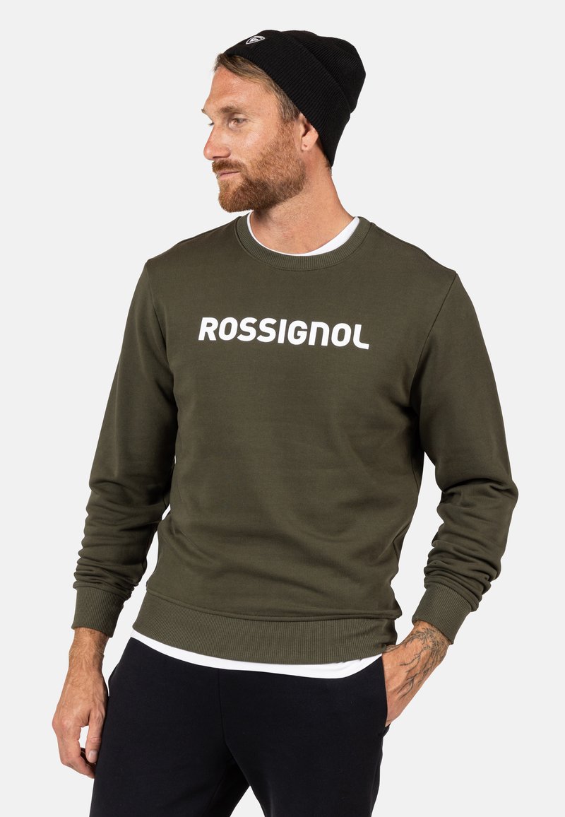 Felpa verde oliva con colletto e polsini a coste, caratterizzata dalla scritta bianca in grassetto "ROSSIGNOL" sul petto. Tessuto morbido.