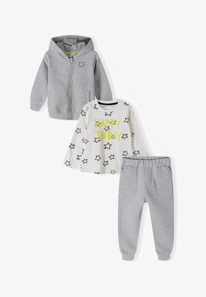 Compleu pentru copii format din trei piese: hanorac gri cu fermoar, tricou alb cu mânecă lungă decorat cu stele negre și text verde, și pantaloni gri asortați cu talie elastică.