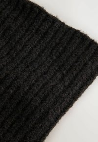 Fekete bordázott kötött anyag, puha, bolyhos textúrával, függőleges vonalakkal és felgöngyölített szélekkel, kiemelve vastagságát és melegségét.
