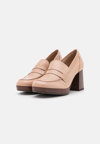 Beige leather loafers with stitched detailing, a rounded toe, and a 2.5-inch wooden block heel. Smooth texture and classic design.