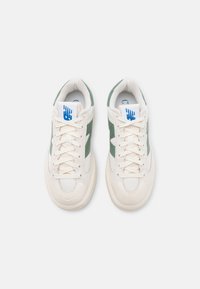 Paire de baskets blanches et vertes à lacets avec semelles rembourrées et logo bleu sur la languette, vues de dessus sur fond blanc.