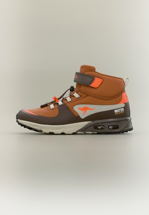 Baskets montantes marron et orange avec semelle noire, logo kangourou, étiquette résistante à l'eau et lacets avec bride Velcro sur fond uni.