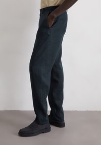 Donkerblauwe broek van een gestructureerde stof, met zijzakken, een rechte pasvorm en gecombineerd met zwarte instappers.
