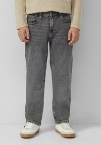 Jean en denim gris avec une coupe décontractée, comportant cinq poches, des coutures visibles et une légère décoloration. Associé à des baskets blanches.