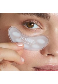 Parche de gel transparente para los ojos con acentos blancos, que cuenta con el texto "KIKO MILANO." Los parches están húmedos y colocados debajo de un ojo.