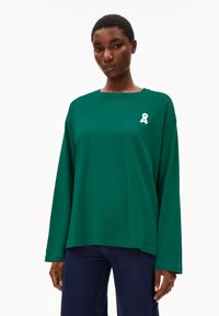 Lange mouwen groene katoenen T-shirt met een ronde halslijn en een witte lintdetail aan de linkerkant. Heeft een relaxte pasvorm.