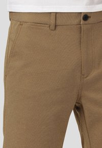 Kaki bukser laget av teksturert stoff med rett passform, med en enkelt knappelukkning og standard frontlommer.
