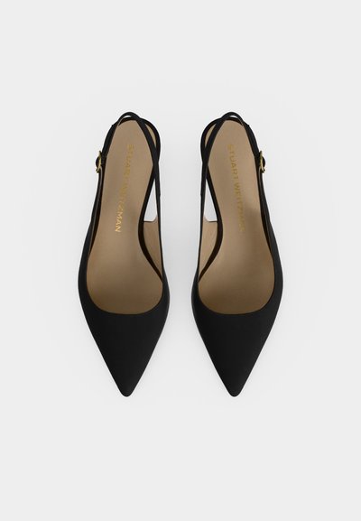 Paire d'escarpins slingback noirs à bout pointu avec fines brides à la cheville et boucles dorées, vues de dessus sur fond blanc.
