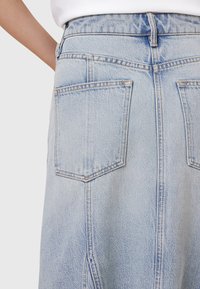 Gonna di jeans azzurri chiari con vita alta, dotata di due tasche posteriori, cuciture a vista e spacco laterale per un tocco in più.