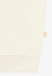 Lichtbeige sweatshirt met ribbels aan de mouwen en onderrand. Heeft een klein, reliëf merklabel aan de zijkant. Zacht, gestructureerd materiaal.