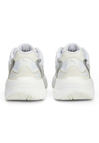 Baskets blanches avec des accents gris, dotées de matériaux texturés, d'une forme arrondie, d'un col rembourré et d'un logo distinctif sur le talon.