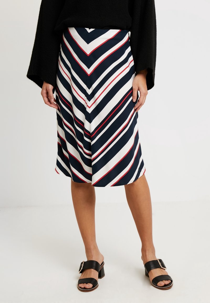 Hamele knee-length, jossa on laivastonsininen, valkoinen ja punainen chevron-kuvio, valmistettu sileästä kankaasta, yhdistettynä mustiin paljetti-korkokenkiin.