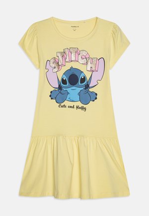Žlté bavlnené šaty s krátkymi puff rukávmi a volánkovým lemom, s modrou grafikou Stitche a ružovým trblietavým textom "STITCH Cute and fluffy."