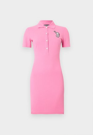 Krátké růžové šaty ve stylu polo s krátkými rukávy, zapínáním na knoflíky vpředu, límečkem a malou vyšívanou grafikou na levé straně hrudi.
