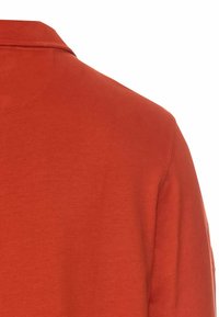 Rød kortærmet polo-shirt med en blød, glat tekstur og en klassisk krave. Har ren syning og et enkelt, umarkeret design.