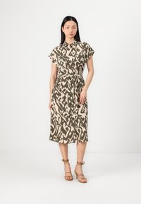 Abito camicia in un motivo astratto beige e oliva, con maniche corte, colletto, tasca frontale e vita legata. Tessuto morbido.