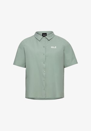 Chemise vert clair à manches courtes avec col et logo blanc Jack Wolfskin sur la poitrine, présentée sur un fond blanc.