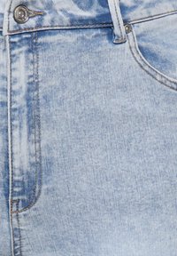 Jean en denim bleu clair avec un bouton à l'avant, une boucle de ceinture et des coutures visibles autour de la poche et de la ceinture.