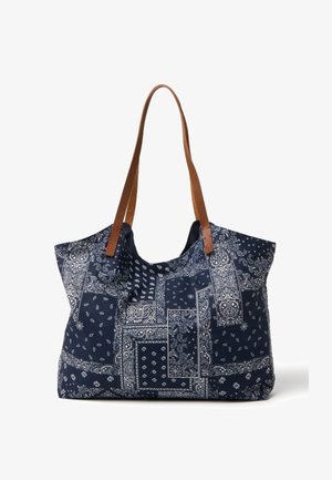 Bolsa tote de tela azul marino con patrones blancos de paisley y patchwork, con correas de hombro de cuero marrón.