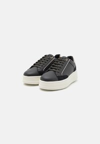 Sneaker in pelle nera con finitura testurizzata, dotati di lacci decorativi con accenti metallici e una suola piatta bianca e spessa.